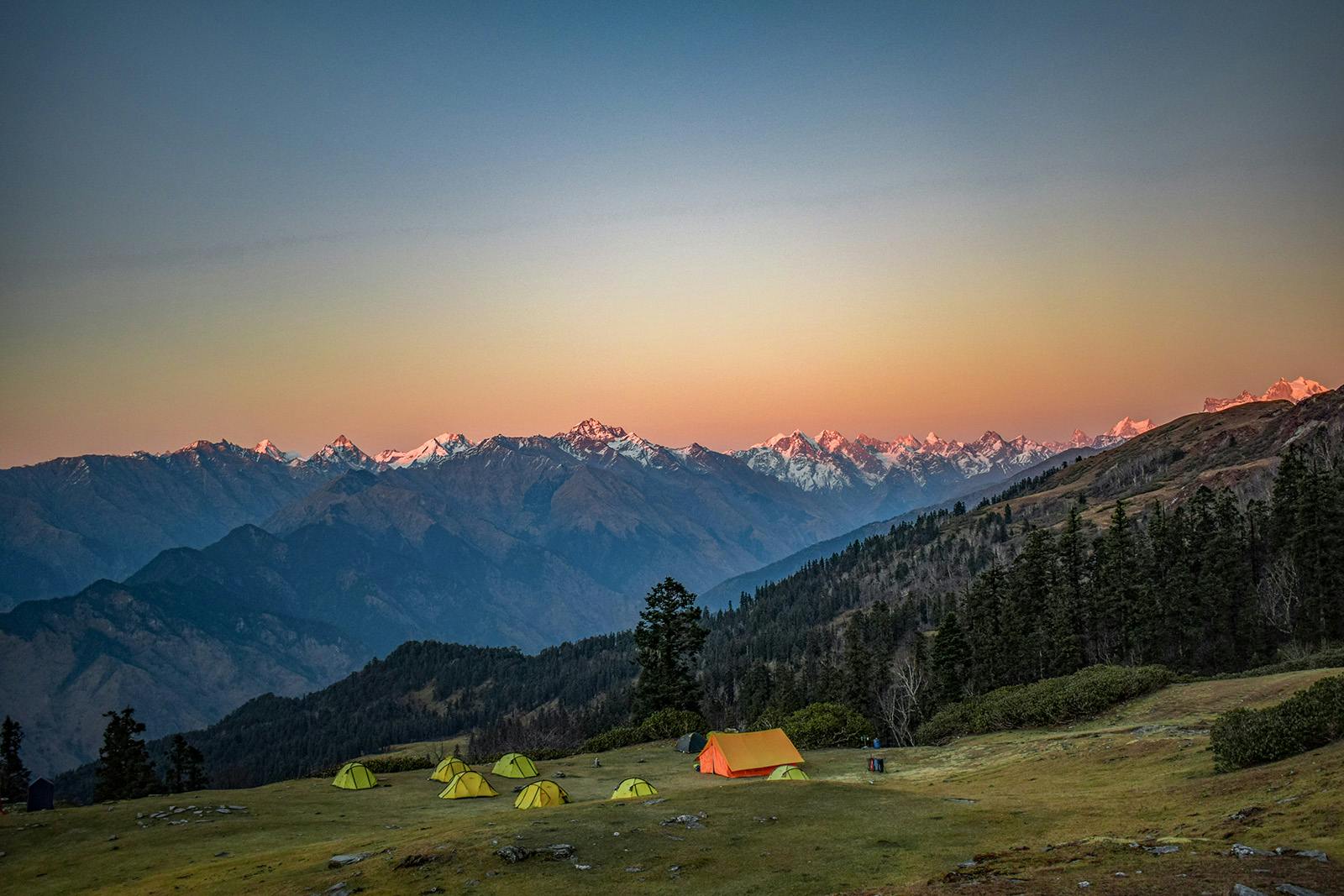 Indiahikes Pushtara campsite with a hazy golden glow of mountains in the backdrop